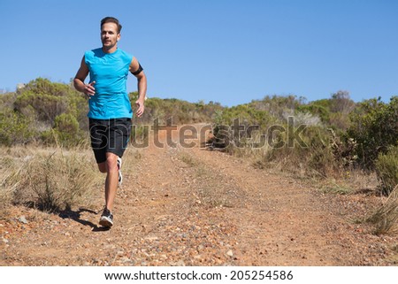 Athletic man jogging on country trail on a sunny day