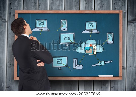 Thinking businessman looking at technology doodles on board