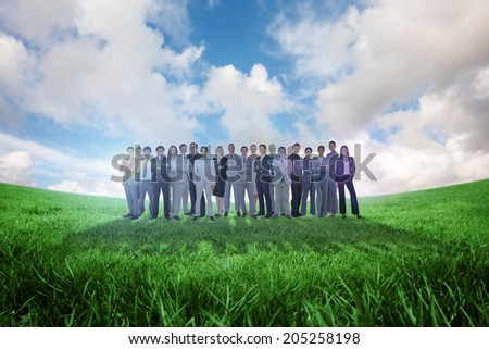 Business people standing up against green field under blue sky