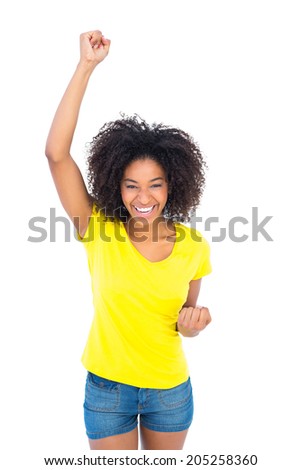Pretty girl in yellow tshirt and denim hot pants cheering at camera on white background