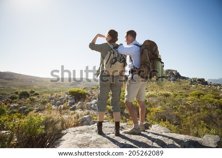 Hiking couple looking out over country terrain on a sunny day