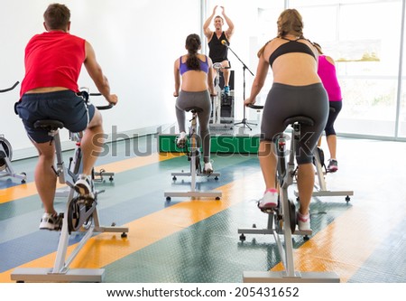 Bike class working out with motivational instructor at the gym