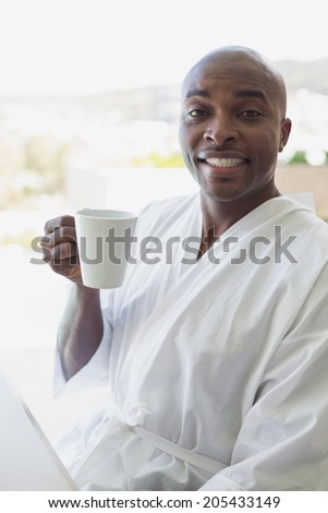 Handsome man in bathrobe drinking coffee outside on a sunny day