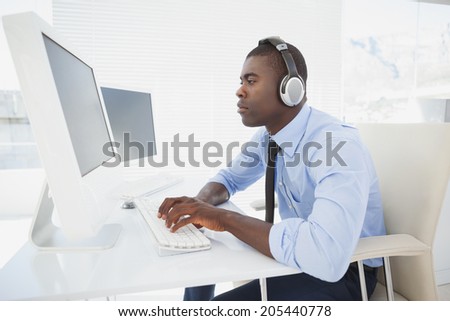 Focused businessman working at his desk listening to music in his office