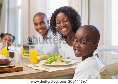 Happy family smiling at camera at lunch at home in the kitchen