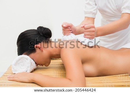 Beautiful brunette enjoying a herbal compress massage in the health spa