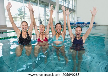 Female fitness class doing aqua aerobics and cheering in swimming pool at the leisure centre