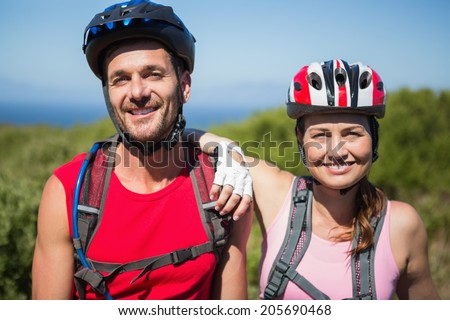 Active couple cycling in the countryside smiling at camera on a sunny day