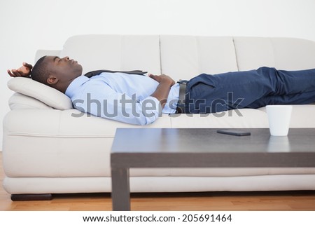 Tired businessman lying on the sofa at home in the living room