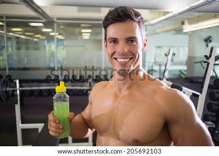 Close-up portrait of a sporty young man with energy drink in gym