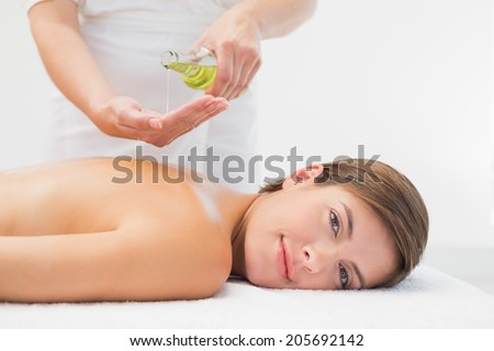 Attractive young woman getting massage oil on her back at spa center