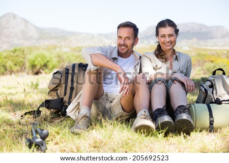 Happy hiking couple taking a break on mountain trail on a sunny day