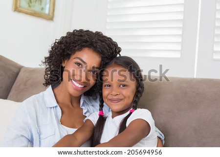 Pretty mother sitting on the couch with her daughter at home in the living room