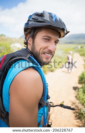Fit couple cycling on mountain trail man smiling at camera on a sunny day