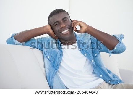 Casual man sitting on sofa on the phone at home in the living room