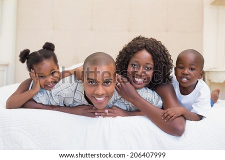 Happy family smiling at camera together on bed at home in the bedroom