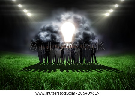 Business people standing up against football pitch with bright lights
