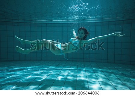 Pretty swimmer looking at camera underwater in bikini in the swimming pool at the leisure centre