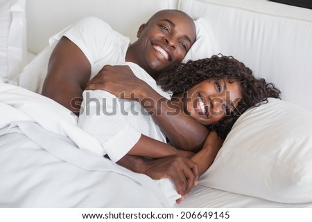 Happy couple cuddling together in bed at home in the bedroom