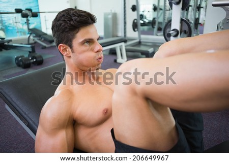 Side view of male weightlifter doing leg presses in gym