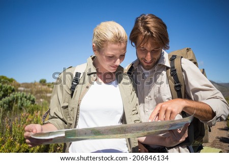 Hiking couple walking on mountain terrain looking at map on a sunny day