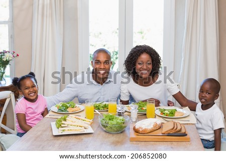 Happy family smiling at camera at lunch at home in the kitchen
