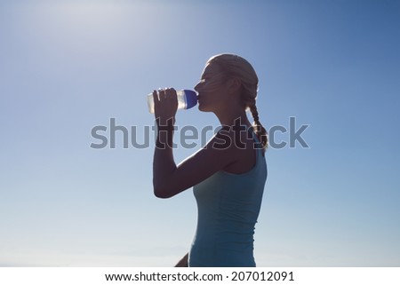 Fit woman drinking from water bottle on a sunny day