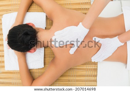 Peaceful brunette enjoying an exfoliating back massage in the health spa