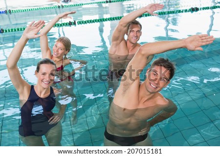Happy fitness class doing aqua aerobics in swimming pool at the leisure centre
