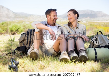 Happy hiking couple taking a break on mountain trail on a sunny day