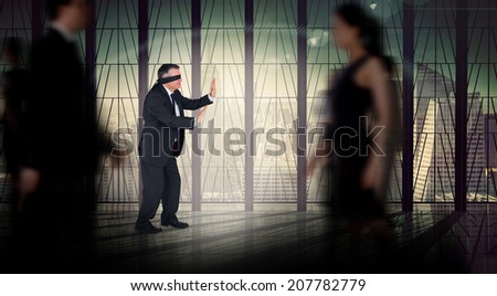 Mature businessman in a blindfold against busy room with large window looking on city
