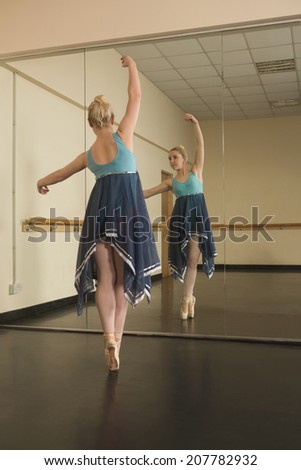 Beautiful ballerina dancing in front of mirror in the dance studio