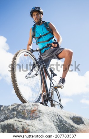 Fit man cycling on rocky terrain on a sunny day