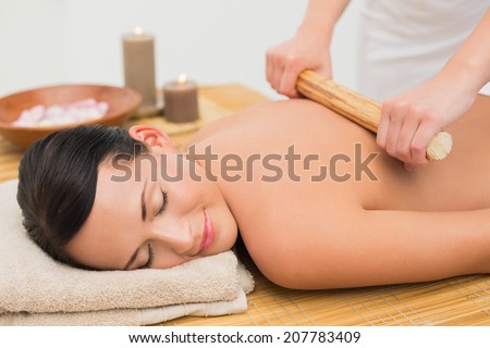Beautiful brunette enjoying a bamboo roller massage in the health spa