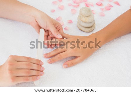 Close up of beautician filing female client\'s nails at spa beauty salon