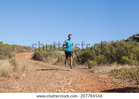 Athletic man jogging on country trail on a sunny day