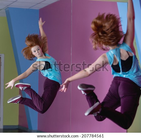 Pretty break dancer jumping up and looking in mirror in the dance studio