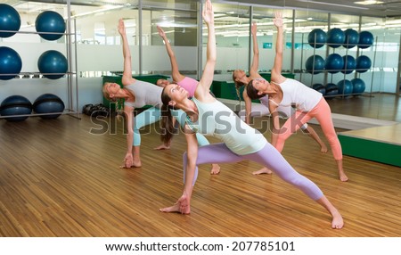 Yoga class in extended triangle pose in fitness studio at the leisure center