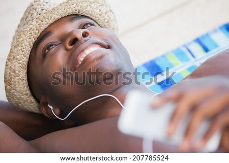 Shirtless man smiling and listening to music on a sunny day