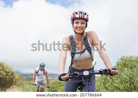 Fit couple cycling on mountain trail on a sunny day