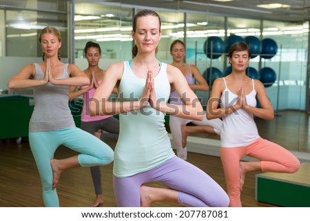 Smiling yoga class in tree pose in fitness studio at the leisure center