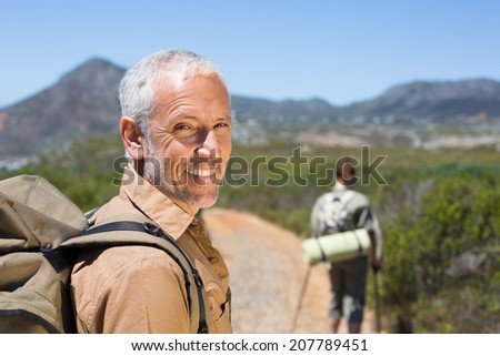 Hiking couple walking on mountain trail man smiling at camera on a sunny day