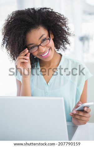 Happy businesswoman working on laptop sending a text in her office