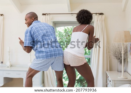 Silly couple dancing on bed together at home in the bedroom