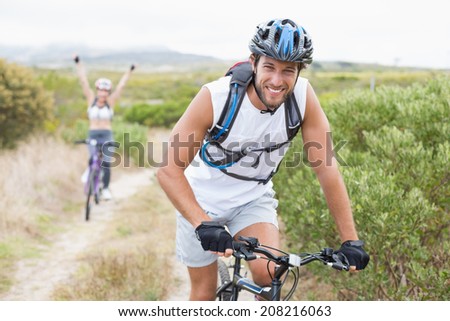Fit attractive couple cycling on mountain trail on a sunny day