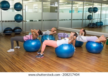 Fitness class doing sit ups on exercise balls in studio at the gym