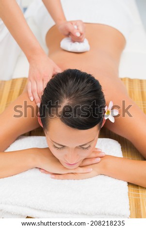 Peaceful brunette enjoying a herbal compress massage in the health spa