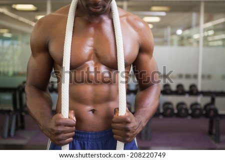 Mid section of a shirtless muscular young muscular man in gym