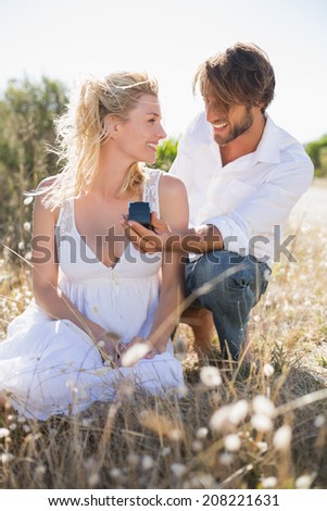 Attractive man proposing to his girlfriend in the country on a sunny day