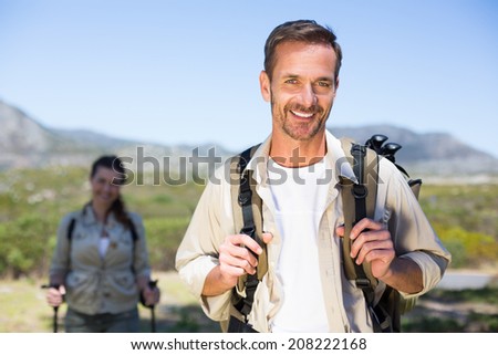 Hiking couple smiling at camera in the countryside on a sunny day
